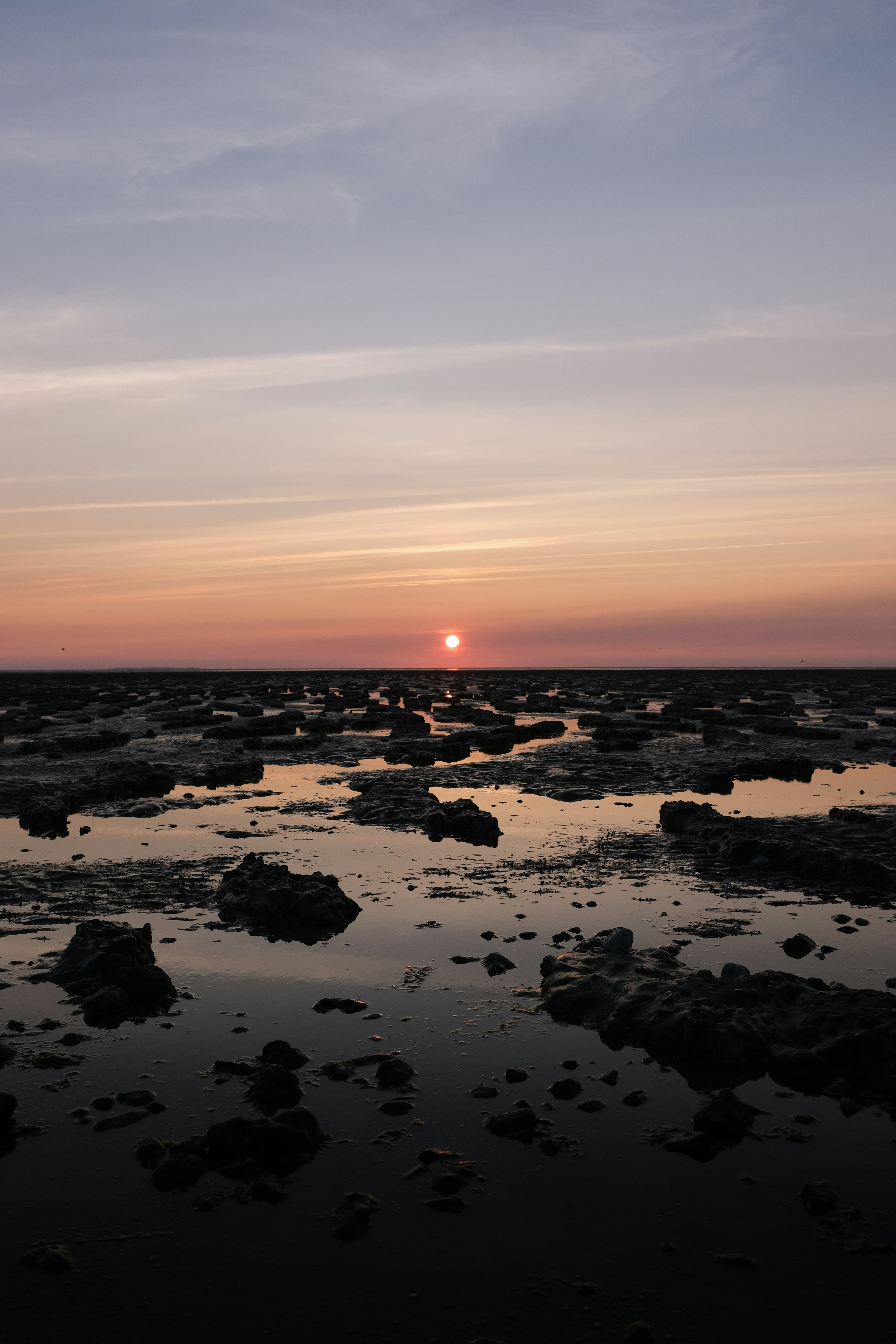 rocks on body of water during sunset